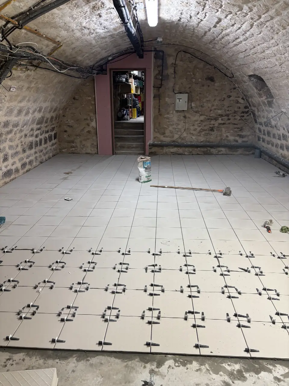 Pose de carrelage en cours dans une cave voûtée en pierre
