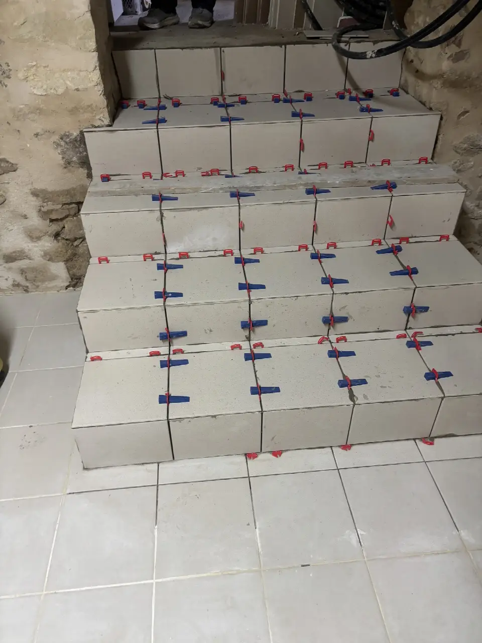 Marches d'escalier en cours de carrelage, avec croisillons de pose