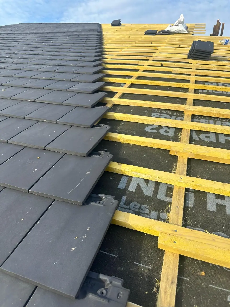 Pose de tuiles plates anthracite sur des liteaux neufs et un écran de sous-toiture