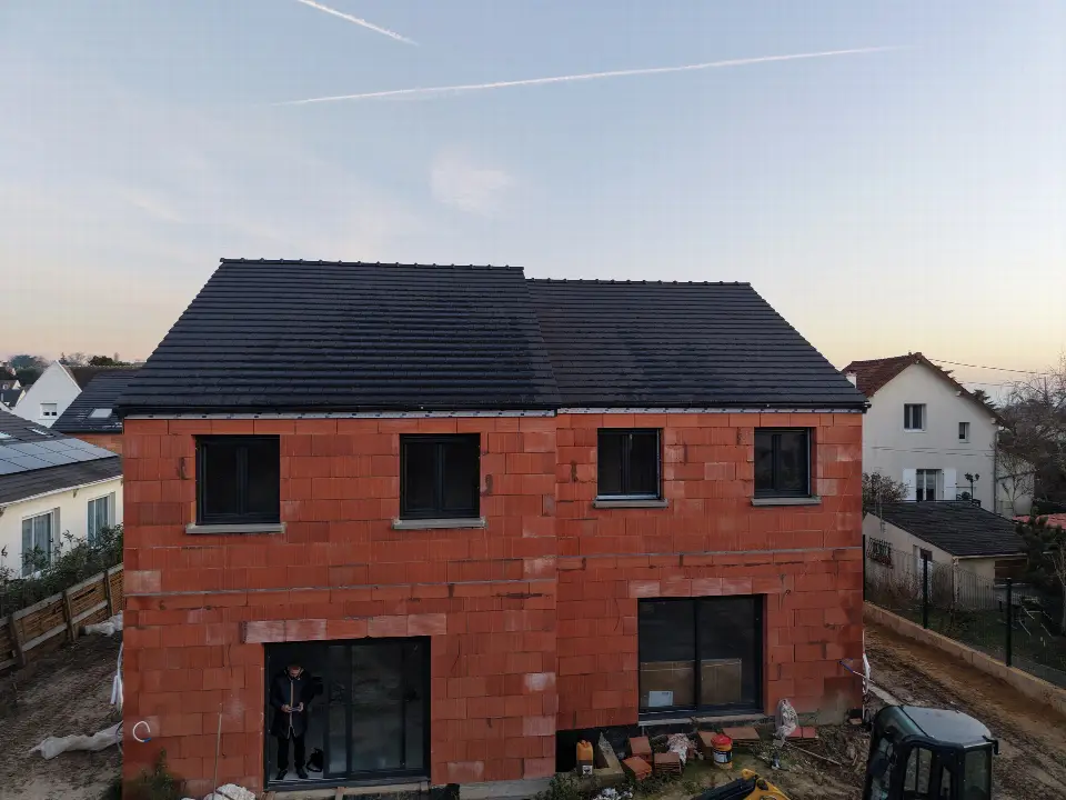 Maison en construction coiffée d'une toiture neuve en tuiles anthracite