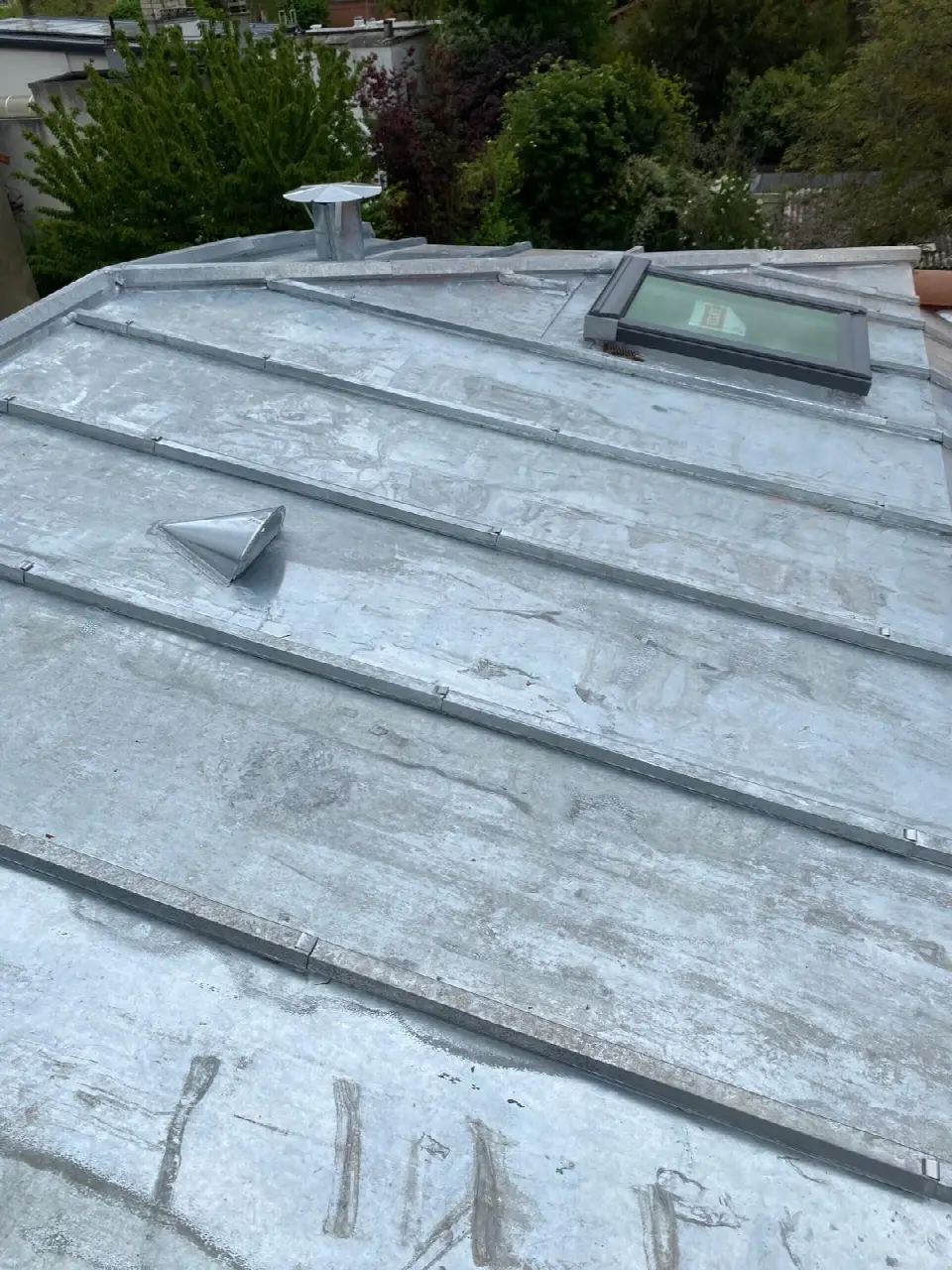 Couverture en zinc à tasseaux avec une fenêtre de toit et des sorties de ventilation